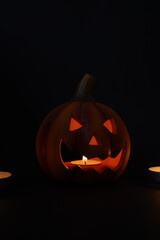 Glowing jack-o-lantern with candle inside, carved pumpkin face shining in dark atmosphere, symbolizing Halloween celebration and spooky tradition