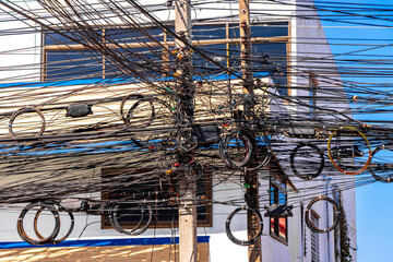 Extreme cable clutter on a power pole  blue sky Thailand.