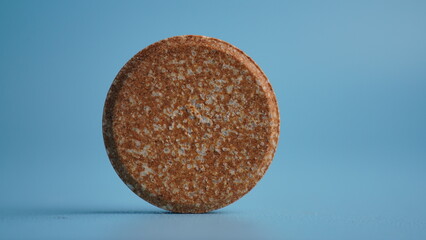 Stack of brown vitamin tablets on blue background