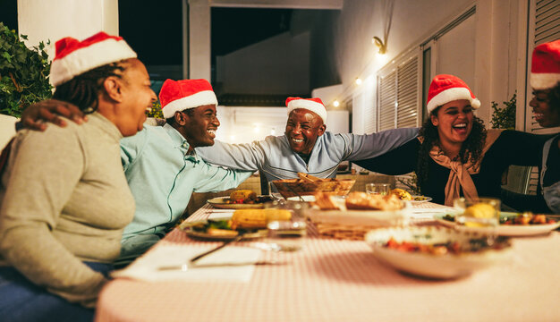 Happy african family having fun eating together during Christmas time - Holiday concept - Main focus on father face