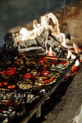 Grilled vegetables on a barbecue grill with a roaring fire in the background.
