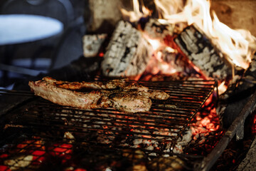 Grilled steak cooking over a roaring fire