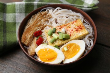 Tasty ramen with enoki mushrooms in bowl on wooden table, closeup