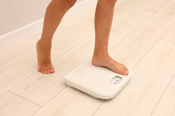 Little boy standing on scales indoors, closeup
