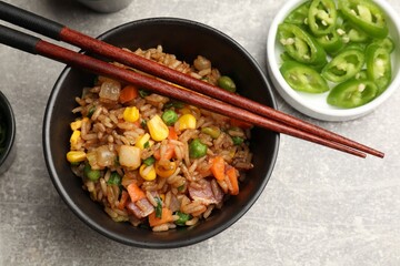 Delicious fried rice in bowl served on grey textured table, flat lay