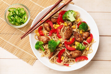 Delicious noodles with meat and vegetables served on light wooden table, flat lay