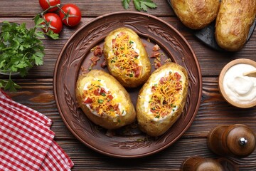 Tasty stuffed baked potatoes, products and spices on wooden table, flat lay