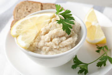 Tasty horseradish sauce with parsley and lemon slices served on light table, closeup
