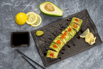 sushi set Philadelphia in avocado with caviar on slate on a gray background 