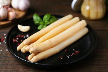 Pickled asparagus and spices on wooden table, closeup