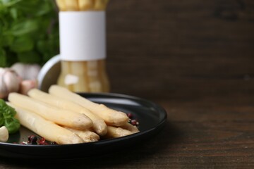 Pickled asparagus and spices on wooden table, closeup. Space for text