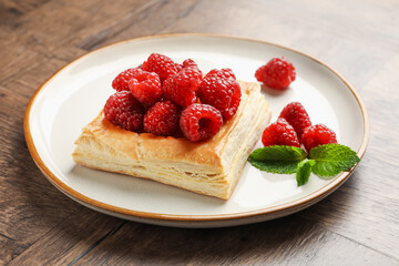 Yummy puff pastry with raspberries on wooden table, closeup