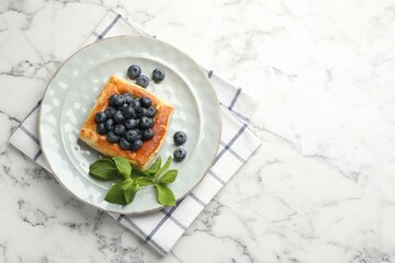 Tasty puff pastry with blueberries and mint on white marble table, top view. Space for text