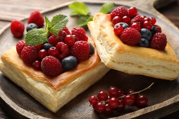 Yummy puff pastries with berries on table, closeup