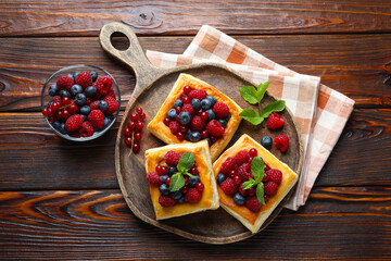 Tasty puff pastries with berries and mint on wooden table, flat lay
