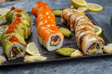 large sushi set Philadelphia different types on slate on gray concrete background macro