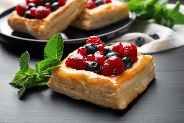 Tasty puff pastries with berries and mint on grey wooden table, closeup