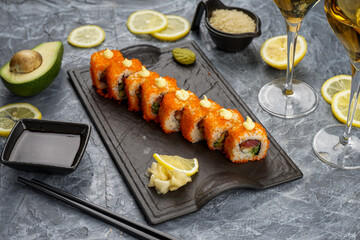 Philadelphia sushi rolls with caviar on a plate on a gray background with wine