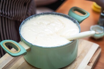Saucepan with risen, fluffy honey dough ready for baking into airy muffins and cookies in a home kitchen