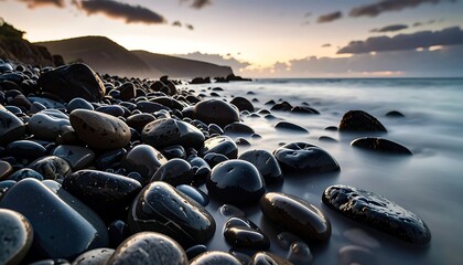 Coastal stones at sunrise, smooth pebbles, dark water