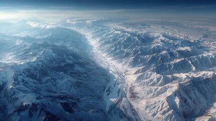 Aerial view of rugged mountain peaks covered in snow during daytime in winter in the Andes mountain range, South America, with a clear blue sky
