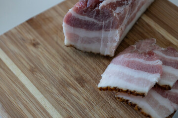 Ukrainian traditional cuisine. Very tasty pieces of salo. Raw ukrainian bacon or salo on wooden board. Sliced salted pork lard (salo). Food concept.
