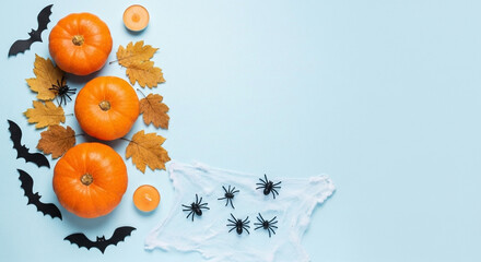 Spooky Halloween flat lay with pumpkins, bats, spiders, and autumn leaves on a pastel blue background