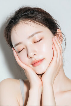 透明感のある美肌の女性が顔に手を添える美容イメージ