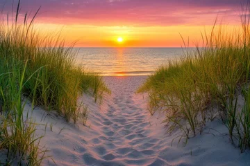 Crédence de cuisine Beige Sandy beach pathway framed by green dune grass leads to calm ocean under vibrant sunset sky, creating peaceful and warm atmosphere by water  © Thanapong