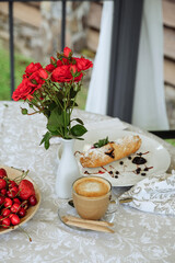Breakfast table with coffee, pastry, and flowers