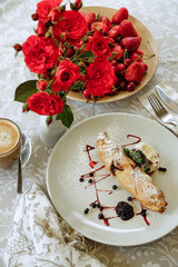 Breakfast scene with strudel, berries, flowers, and coffee