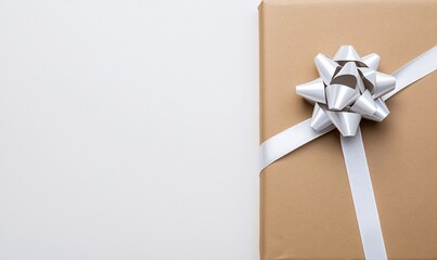 Gift box with silver ribbon and bow on brown paper, white background
