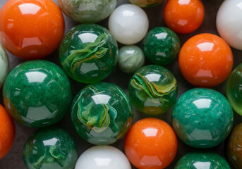 A vibrant collection of marbles in various sizes and colors, including green, orange, and white, creates a visually appealing mosaic of textures and patterns, showcasing the beauty of childhood play