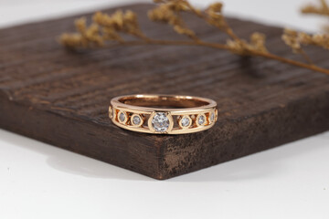 Close-up of an elegant gold diamond band ring placed on a wooden surface, showcasing luxury fine jewelry design.