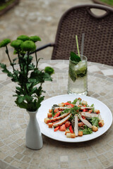 Fresh salad with chicken and a refreshing drink on a table