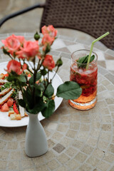 A refreshing cocktail and salad with flowers on a mosaic table.