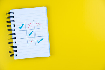 Notebook page showing tic tac toe with red crosses and blue ticks, creative concept of decision making and problem solving