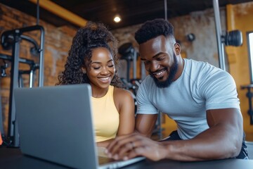 Two fit young people in a gym, with the man operating a laptop that shows their workout data while the woman smiles, suggesting they are discussing their performance and setting new goals.