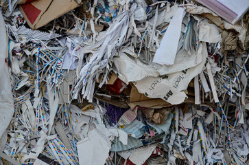 A detailed, abstract close-up of a pile of shredded paper and cardboard scraps collected for recycling. The image highlights the recycling process and sustainability efforts.