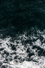 A captivating view of dark ocean water with white foamy waves, showcasing the dynamic and powerful beauty of nature's aquatic landscape.