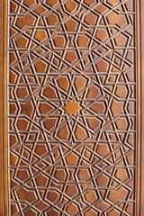 Close-up of Islamic geometric wood carving on a Mosque door, showing star pattern and texture. 