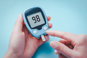 Close-up of a hand using a blood glucose meter, showing a healthy blood sugar level, perfect for diabetes awareness, healthcare, medical articles, or wellness and nutrition concepts.