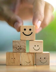Hand placing a happy face wooden block on a stack of similar blocks