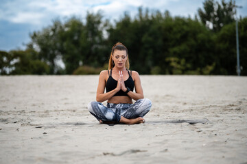 Fitness model practicing yoga on the beach: finding inner peace and mindfulness