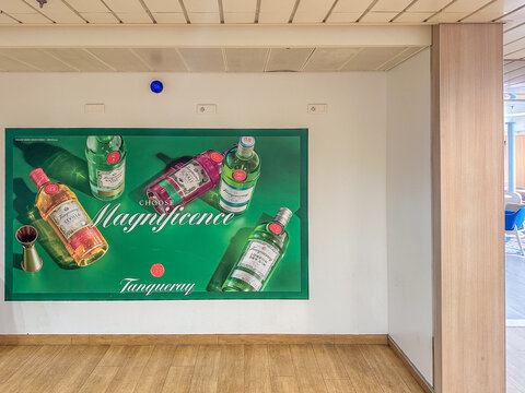 Promotional poster for Tanqueray gin with colorful bottle visuals displayed in DFDS ferry interior