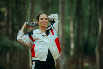 Woman Wearing Tracksuit Ties Her Hair with a Scrunchie. happy Jogger taking a break to do a stylish ponytail 
