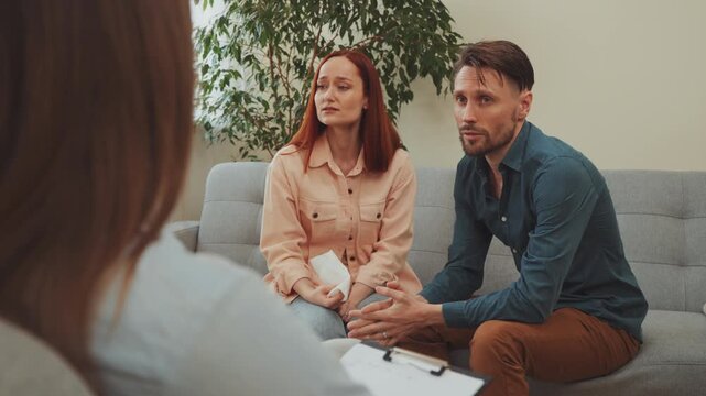 Emotional couple at therapy session, woman crying with tissue while man talks to counselor, seeking support and guidance