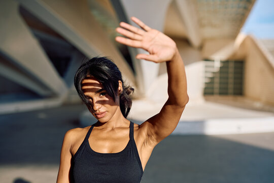 Sportswoman shielding her face from the bright sunlight with her hand while enjoying the stunning architecture