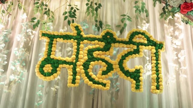 Traditional "Haldi" sign in Hindi, made of marigold flowers, for an Indian wedding pre-wedding ceremony backdrop decoration.