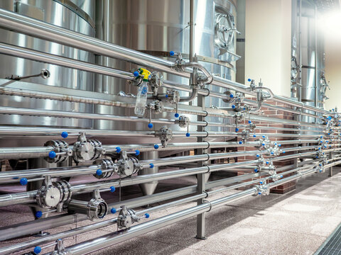 Stainless steel brewery pipes and valves in modern beer production plant for industrial beverage manufacturing, clean processing systems, fluid control, food-grade equipment, alcohol technology.
